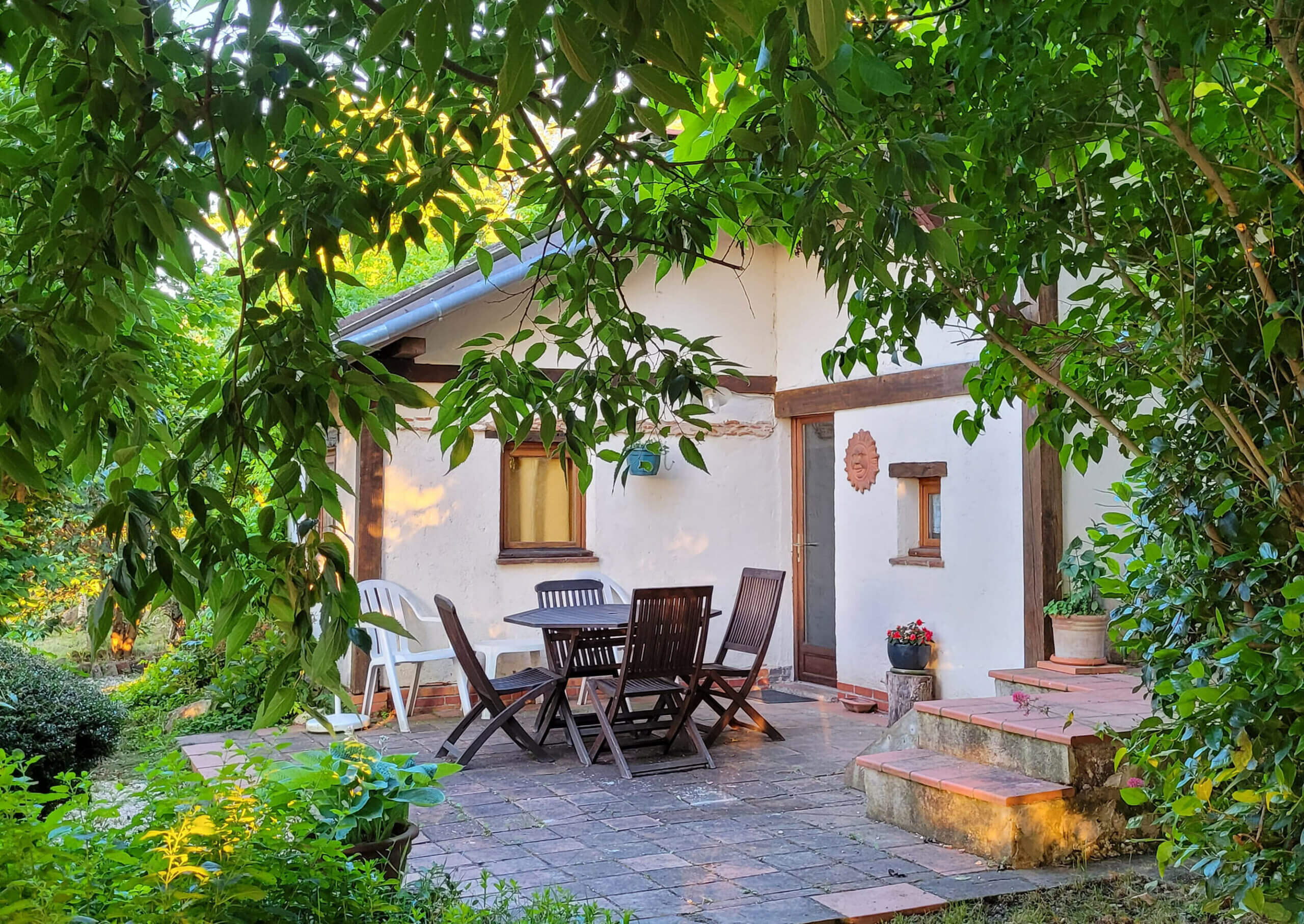 terrasse ombragée avec table et chaises en bois gîte Ostal